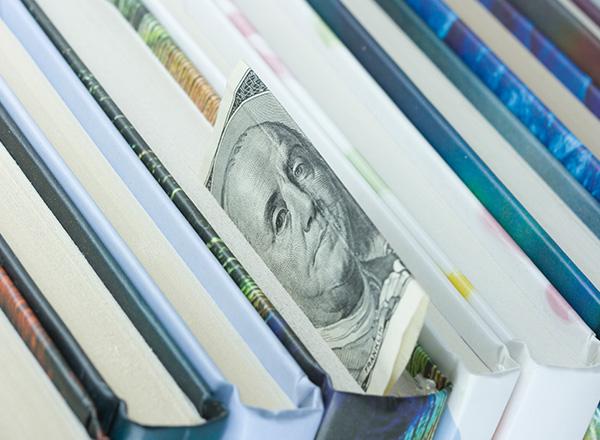 Decorative image of $100 dollar bill used as bookmark in a textbook.