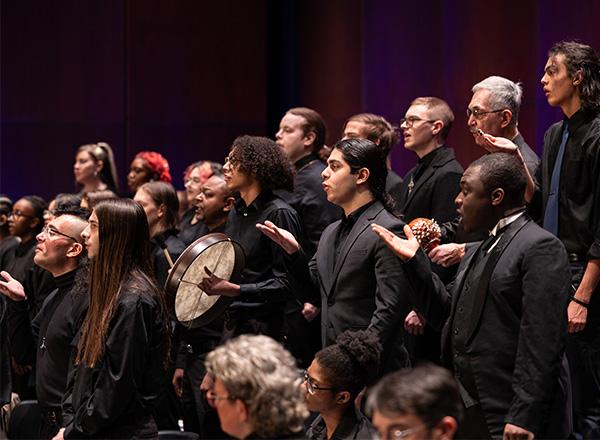 A group of people dressed in black formal attire singing. 