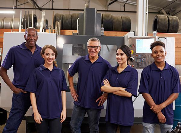 Engineers and training apprentices in front of a CNC machine.
