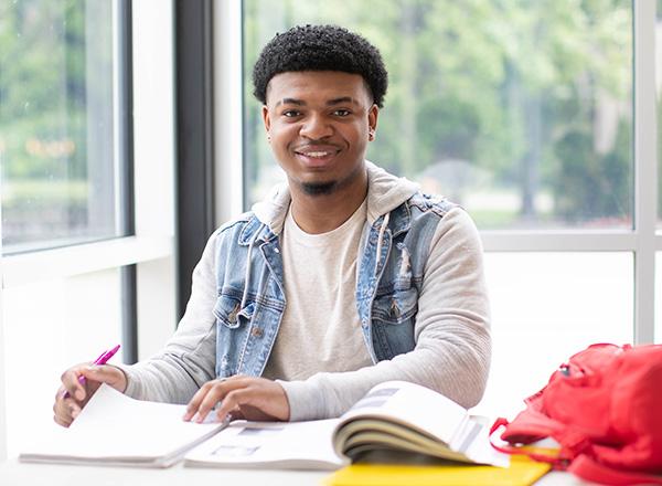 Student smiling and working on paperwork.