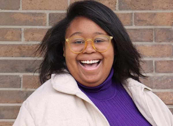 A headshot of Sydney Lane against a brick wall.