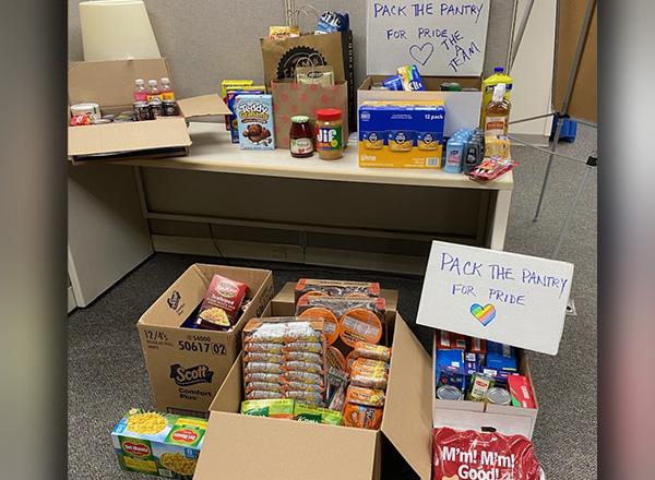 Donated food in boxes and bags with signs that read "Pack the Pantry"