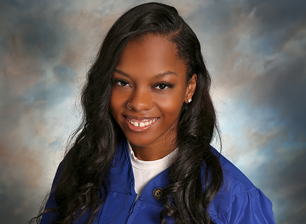 Headshot of Summer Brooks who has long brown hair and wearing a blue grad gown.