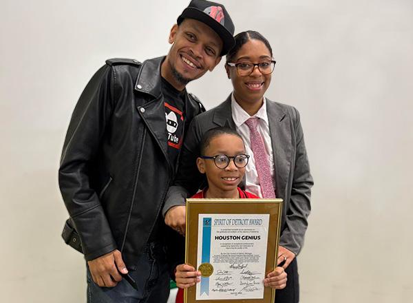 Houston with his parents, holding up his award.