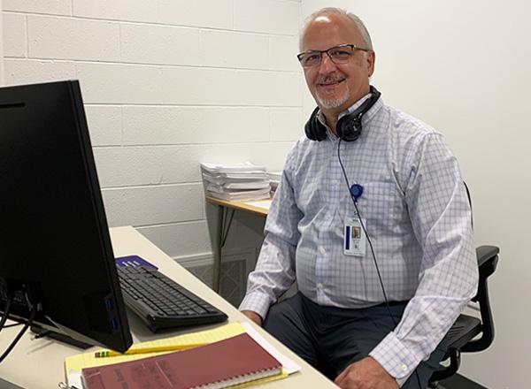 Tony Conti sits at his desk, wearing headphones for CIS.