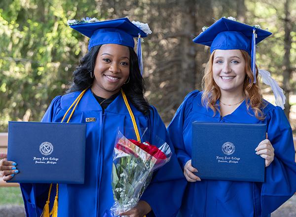 Two HFC female graduates holding their diplomas.