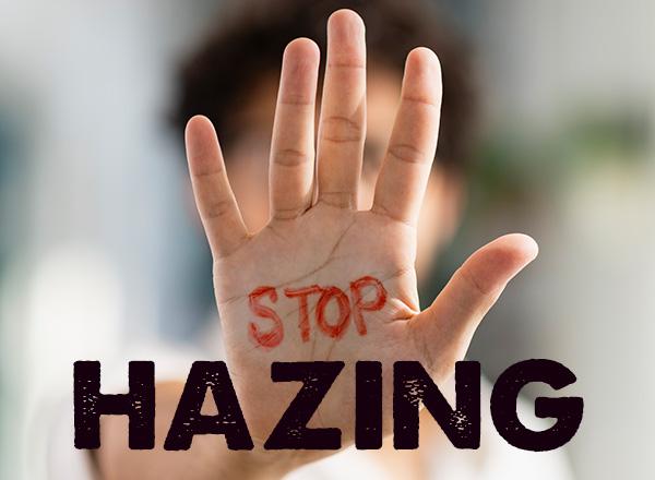 A man holding his hand out to the camera, written on it is "STOP" in red marker below that HAZING in bold.
