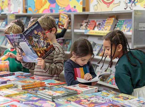 Children looking over books at a book fair.