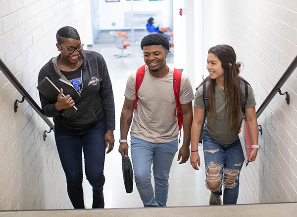 Students smiling and walking up stairs. 