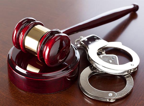 Gavel and handcuffs on wood table. 