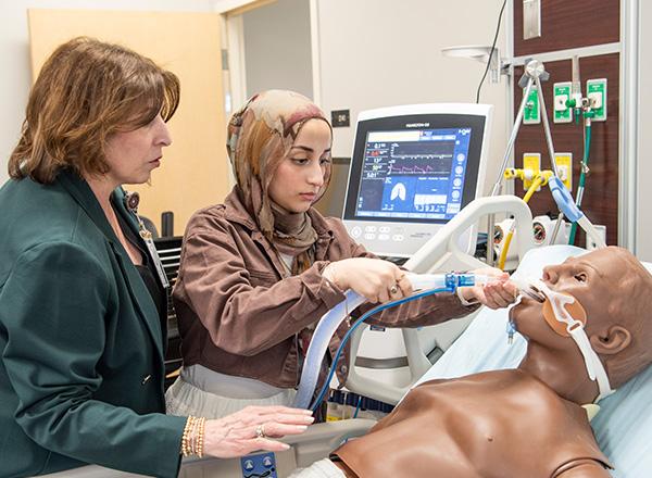 Respiratory therapy instructor and student practicing on dummy.