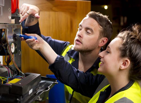 An electrician and apprentice examining electrical wires
