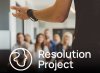 A person presenting to a crowd with their left arm extended out; the crowd is blurred. Resolution Project logo over top of image. 