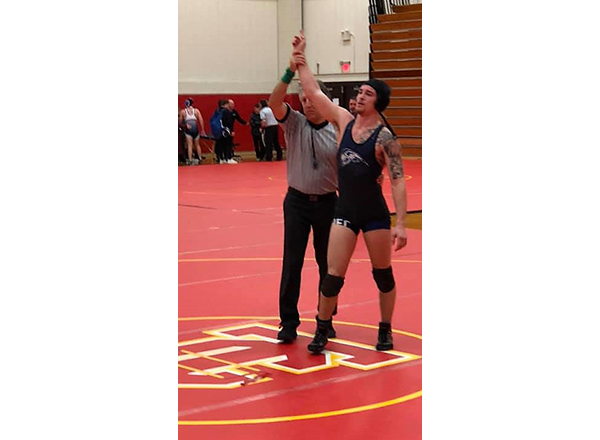 Dominic Mancina on the wrestling mat, arm raised in victory