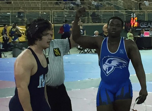 Jeffrey Henderson (right) has his arm raised in victory by referee. Henderson became the first All-American wrestler at HFC in March. 