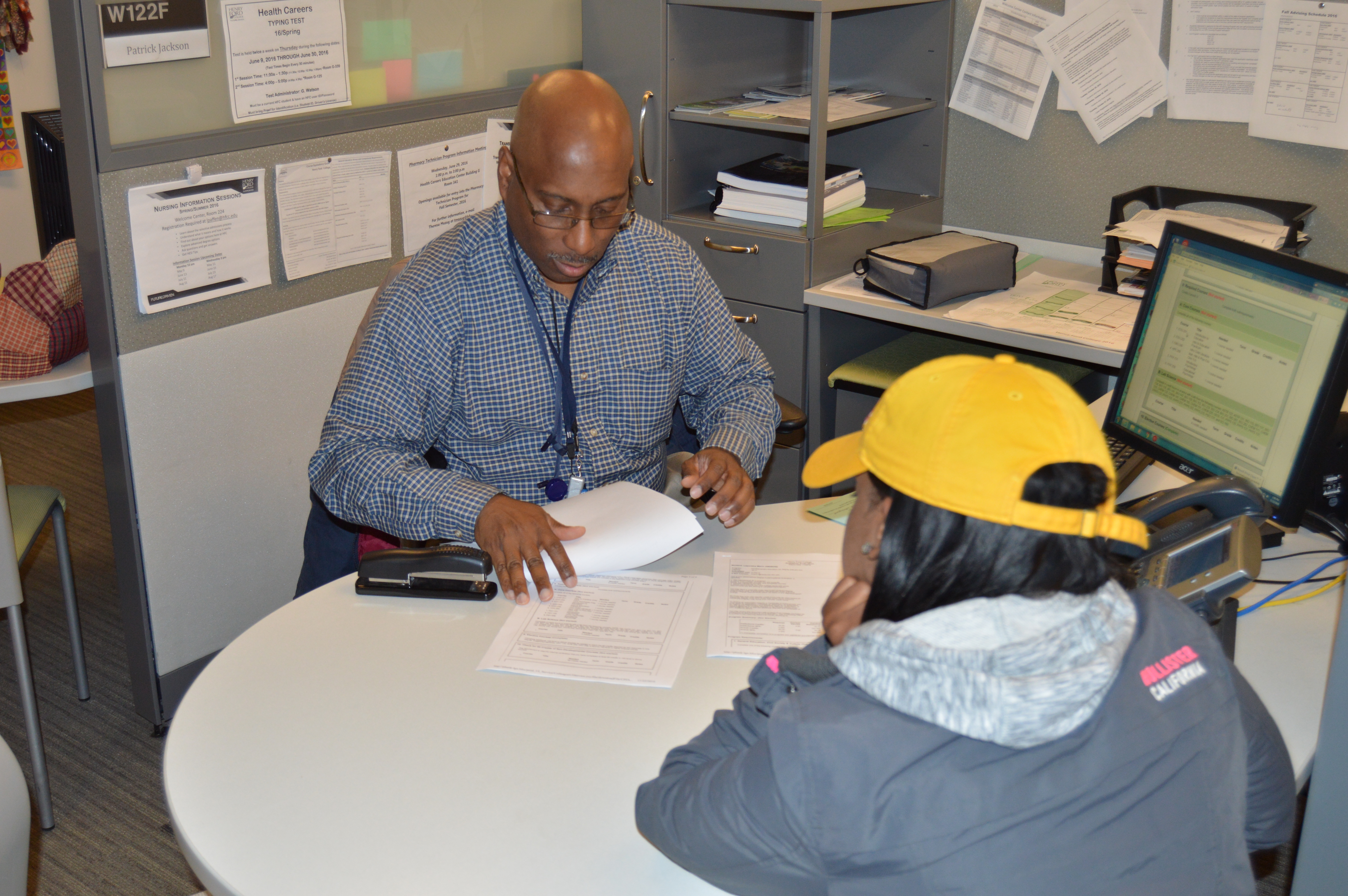 Student sitting at a circular table with advisor going over course schedule and program information